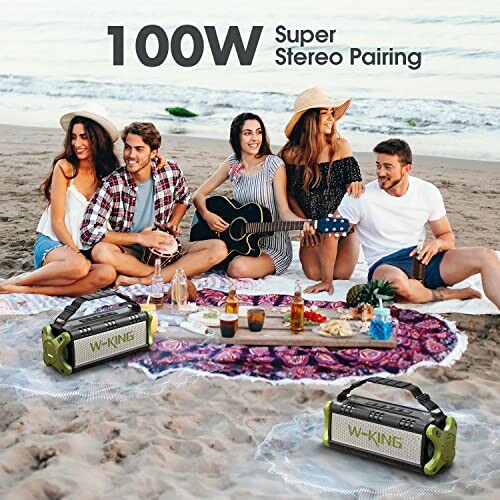 Group of friends at a beach picnic with portable speakers and a guitar.