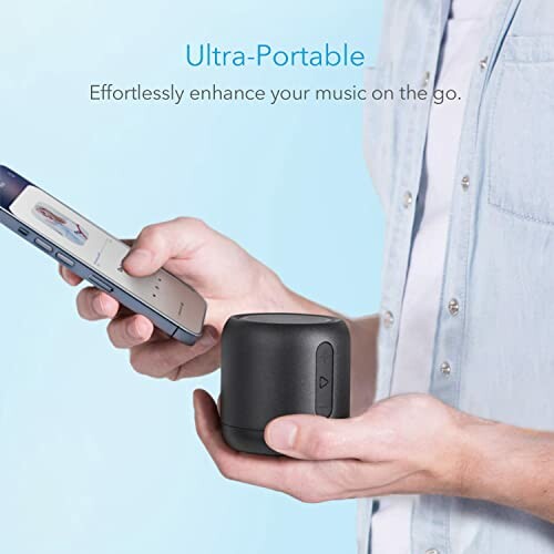 Person holding a small portable wireless speaker and a smartphone.