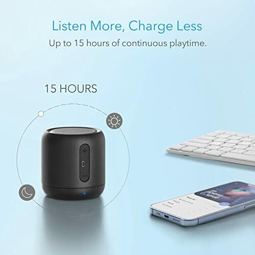 Compact wireless speaker with 15 hours of playtime next to a smartphone and keyboard.