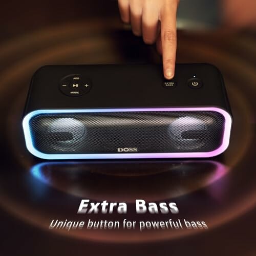 Finger pressing button on wireless speaker with extra bass feature.